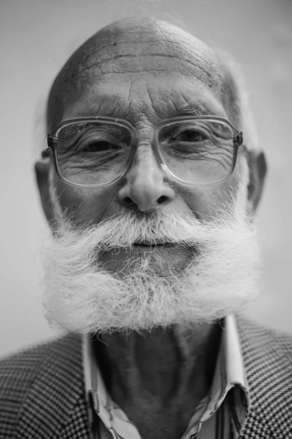 Black and white portrait of an older man with a white beard and glasses.
