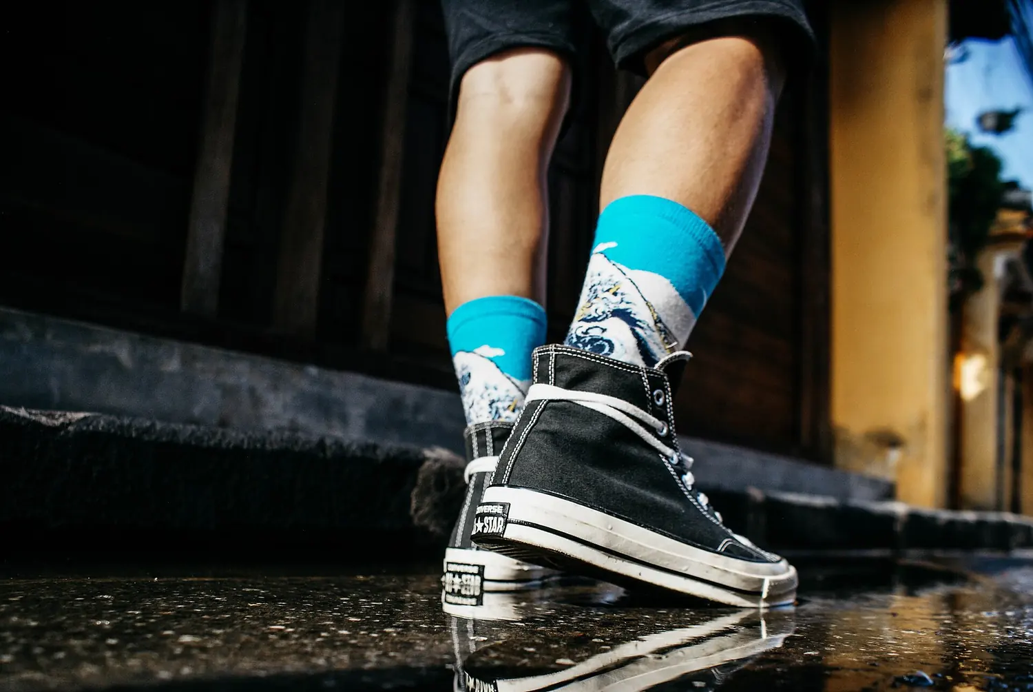 Black sneakers and blue socks on a wet step, shot from low down.