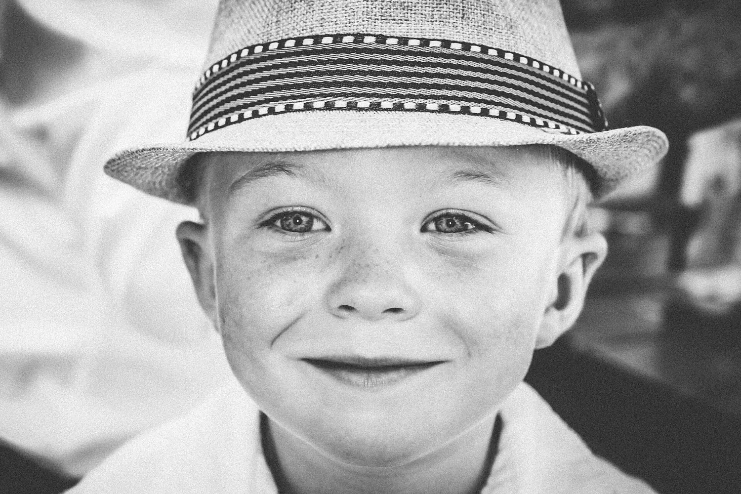 Black and white portrait of a smiling boy in a straw hat.